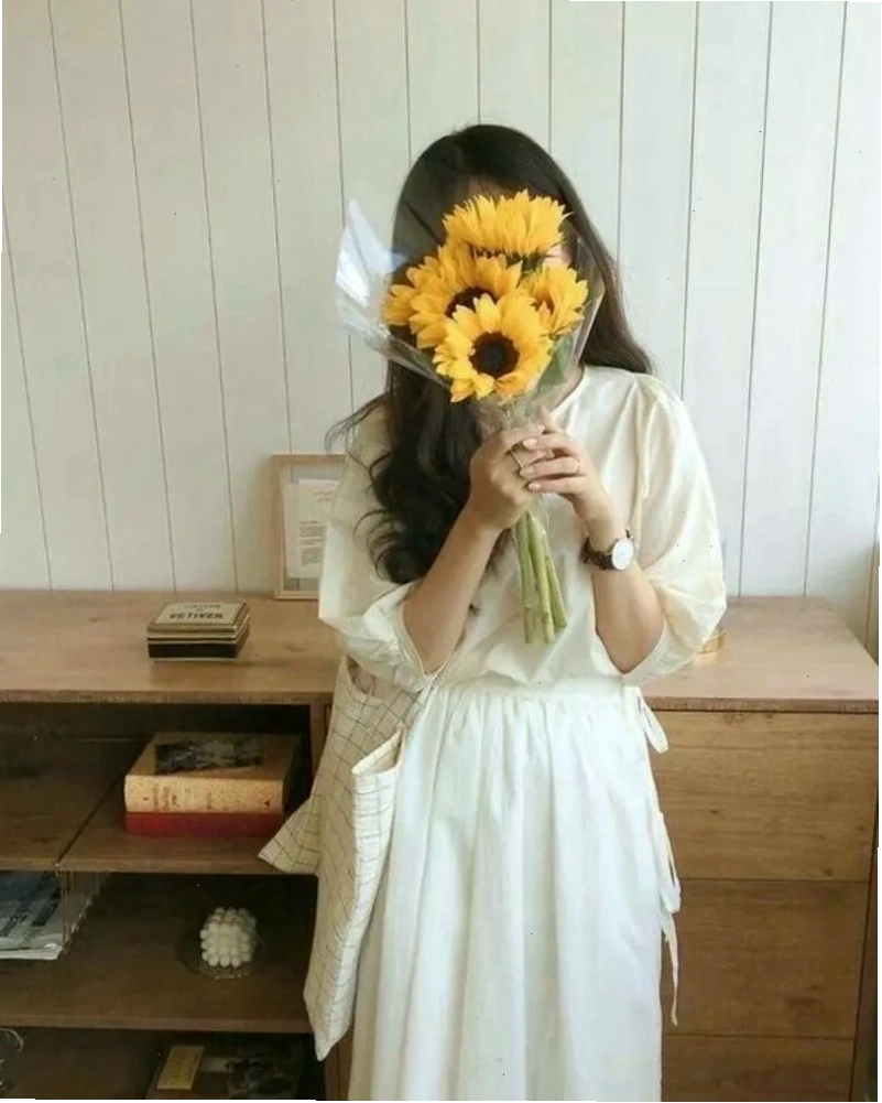 Cô gái xinh đẹp che mặt bằng hoa hướng dương, mang lại năng lượng tích cực và sự tươi mới